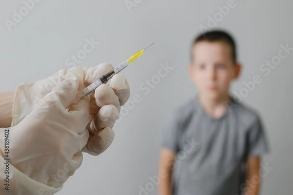 Fototapeta Doctor preparing vaccination injection with a syringe to an afraid child boy. Vaccination of children at school concept.