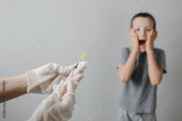 Fototapeta Doctor preparing vaccination injection with a syringe to an afraid child boy. Vaccination of children at school concept.