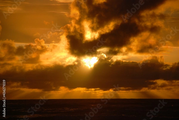 Fototapeta Setting Sun Breaking Through Clouds