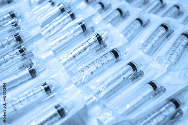 Fototapeta Medical syringes in a package. A bunch of unused, packaged syringes.Many new syringes lie strewn on a flat surface.