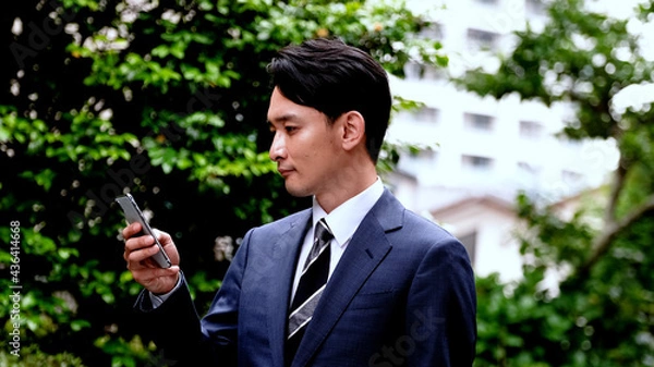 Obraz 屋外でスマホを操作するビジネスマン