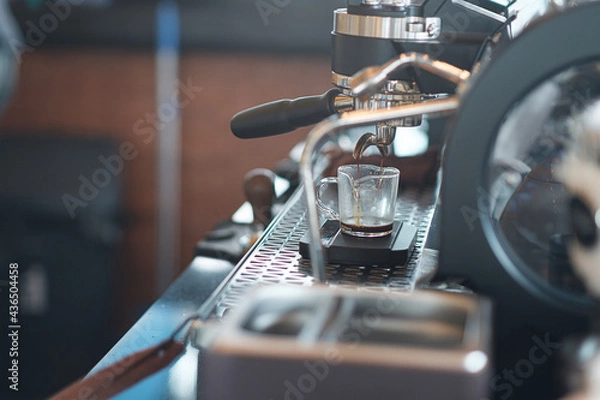 Fototapeta The coffee that is flowing into the cup from the espresso machine.