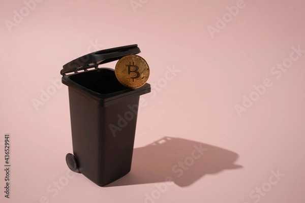 Fototapeta a creative depiction of a falling bitcoin in a container on a pink background