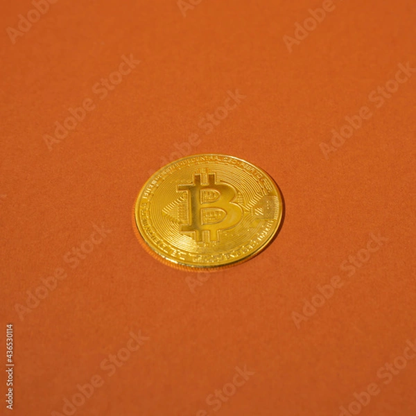 Fototapeta Gold bitcoin is placed on an orange background.