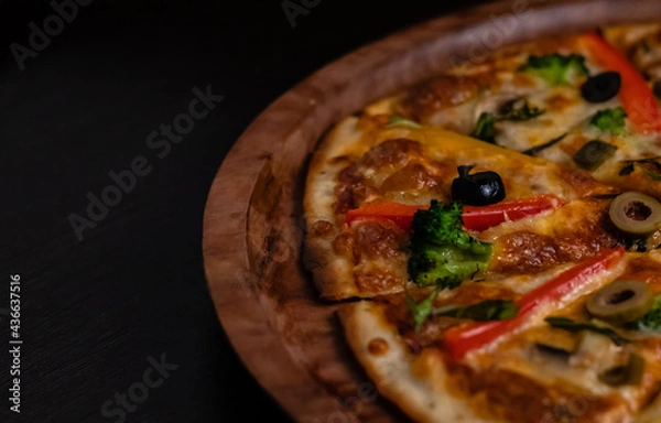 Fototapeta Crop and high angle view of picante pizza on black surface.