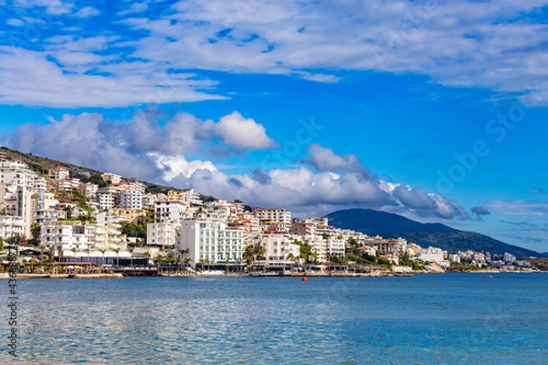 Obraz Panoramic view of Saranda bay and town and hotels along the coast, Albania. Sunny summer day. Beautiful clouds in the sky. Albanian mountains visible on the horizon. Calm blue sea.