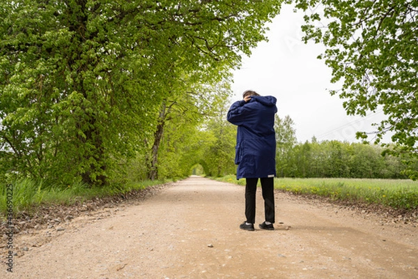 Fototapeta Man in black pants on a blue plait stands on the road