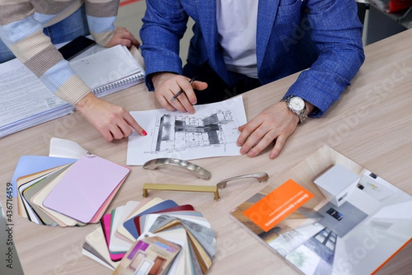 Fototapeta the designer approves the layout of the kitchen set made of laminated MDF. selection of furniture handles for the furniture with the client in the office.