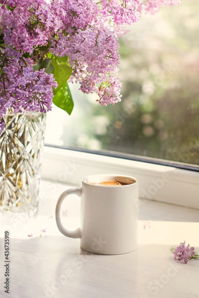 Obraz A bouquet of flowers on the window and coffee in a white cup in the rays of sunlight. A bouquet of lilacs and a cup of coffee.