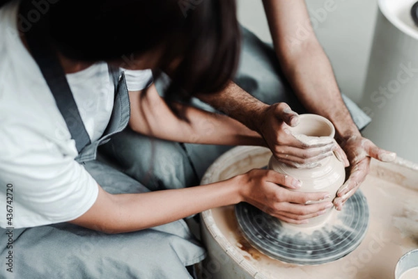 Obraz Modeling a pot on a potter's wheel. Male and female hands close up. A date in a hobby workshop