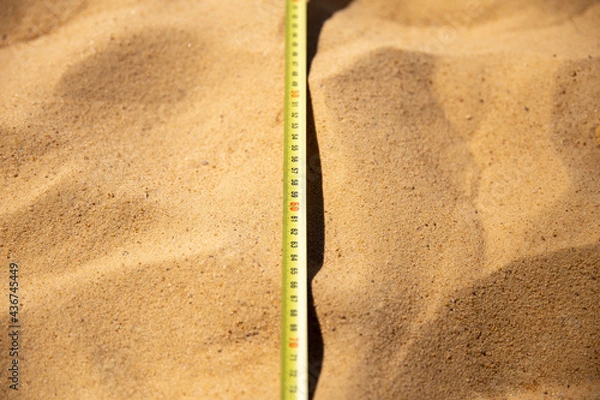 Fototapeta Tape measure lying on the sand, long jump competitions. Length measurement, dimensions of the sports field