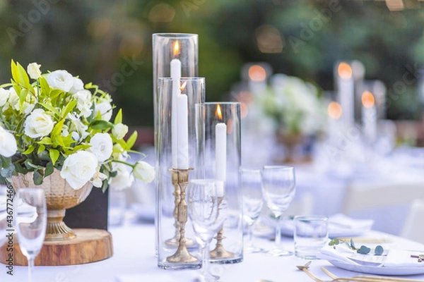Fototapeta Romantic Wedding Table Top Layout Table Spread no people tropical location with gold cutlery white table cloth and scenic view of sunset with copy space tablescape, beautiful paradise setting