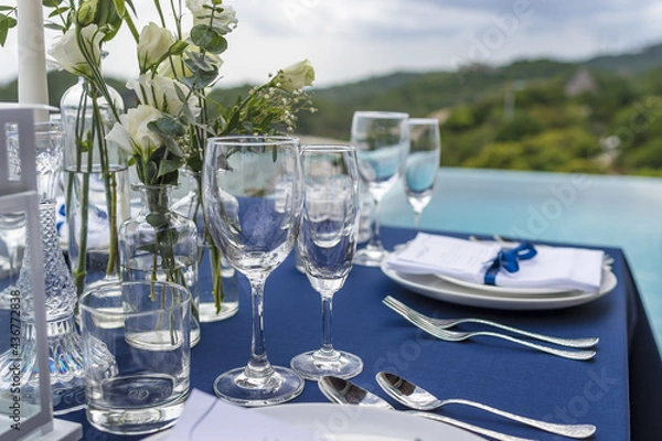 Fototapeta Blue and Silver Romantic Wedding Table Top Layout Table Spread no people catering, event, decor in a tropical location with the sea and clouds in the background