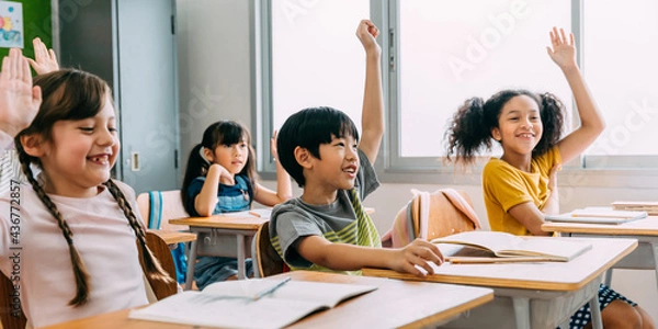 Obraz Elementary age Asian student boy raised hands up in class. Diverse group of pre-school pupils in elementary age in education building school. Volunteering and participating classroom concept.