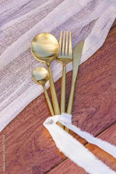 Fototapeta Romantic Wedding Table Top Layout Table Spread with flowers no people with gold cutlery white table cloth and scenic view of sunset and blue skies with copy space tablescape