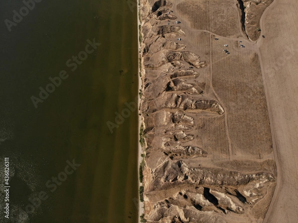 Fototapeta View from above of high clay mountains and rocks and near the Dnieper estuary and Black Sea. There are cars on the hills. Stanislav, Grand Canyon of Kherson region, Ukraine.