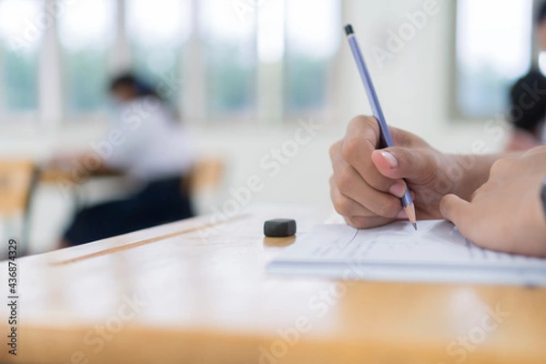 Fototapeta Girl Student in exam test school, Side View of high school or university holding writing document paper answer sheet and lecture final exams in classroom with white uniform pupil of Thailand