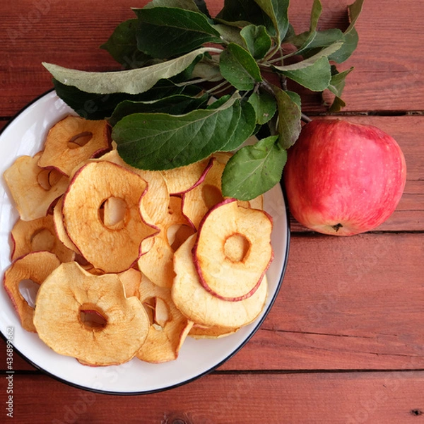 Fototapeta Homemade sun-dried organic apple slices, crispy apple chips, on an old rustic wooden table with fresh apple. Healthy snack. The concept is a healthy diet. Chips are part of a vegetarian diet.