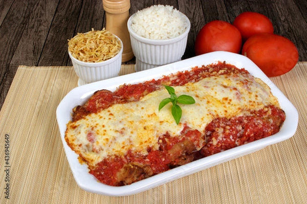 Obraz Steak Parmegiana or Parmegian Filet, made with breaded beef, red tomato sauce, mozzarella cheese and gratin Parmesan. Gourmet close-up photo. White rice and straw potatoes to accompany the food.