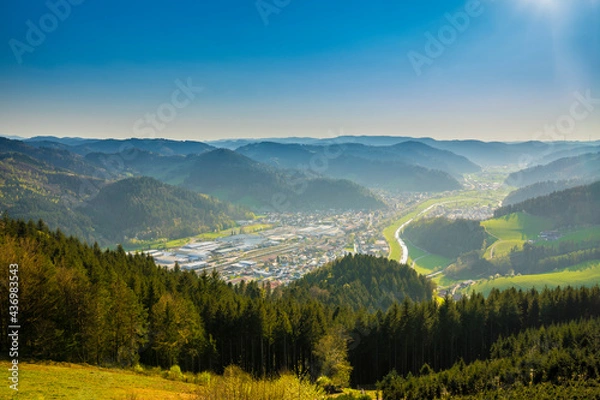 Fototapeta Germany, Aerial drone view above endless valley surrounded by green tree covered mountains and houses of city hausach im kinzigtal