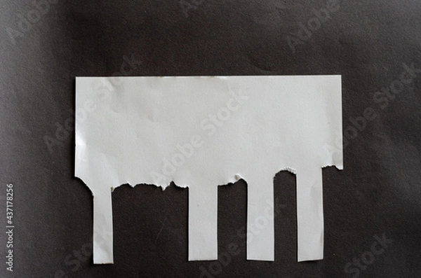 Fototapeta White blank sheet of paper with tear-off tabs on gray background. Crumpled sheet of paper with irregular stripes.