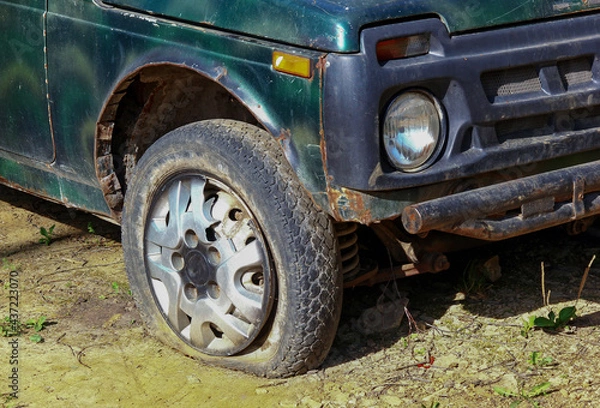 Fototapeta the front wheel of an abandoned green passenger SUV after a serious crash close-up.