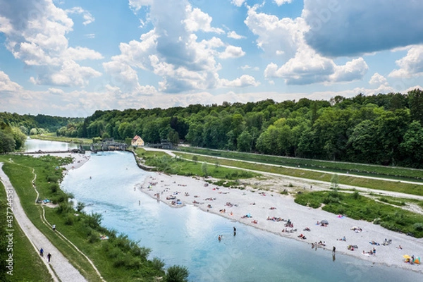 Fototapeta Blick auf die Isar von der Großhesseloher Brücke bei München mit Menschen beim Baden im Frühling / Sommer an Kiesstrand