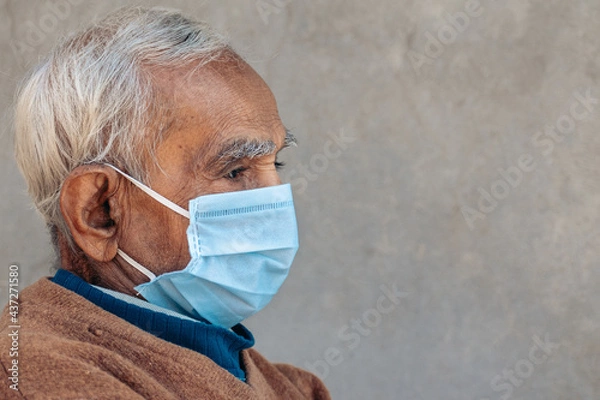 Obraz Side face portrait of old Indian man wearing protective mask during corona virus pandemic in 2021. Concept of geriatric care. With copy space in background
