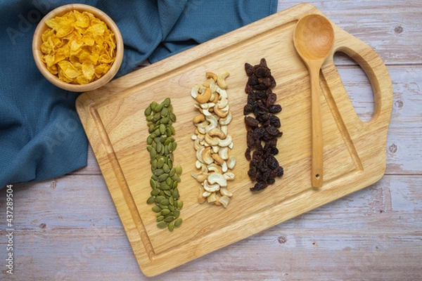 Fototapeta Grains in wooden tray, Currant,Cashew nut,Pumpkin seed,And Cornflakes in wooden cup on wooden floor background.
