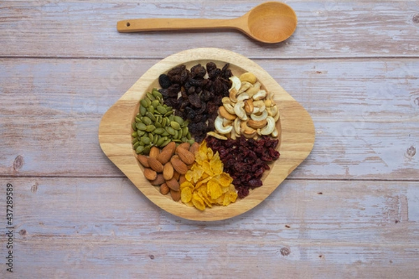 Fototapeta Grains in wooden circle tray, Currant,Cashew nut ,Almond,Pumpkin seed,Cranberry dried fruit, And Cornflakes on wooden floor background.