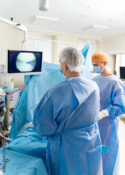 Fototapeta Operating room with surgery in progress. Medical team performing surgical operation in bright modern operating room