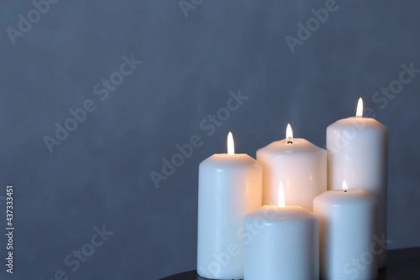 Fototapeta A group of white candles arranged in a tiered arrangement on a plain background.
