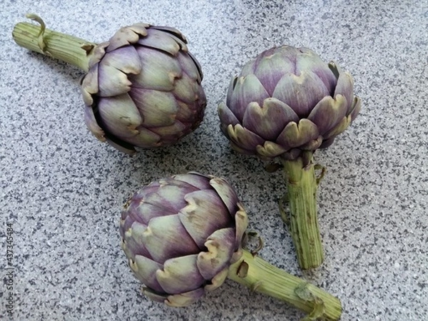 Obraz three purple artichokes displayed on a table