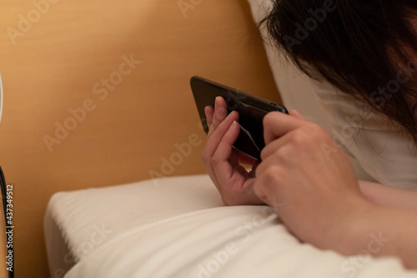 Obraz ベッドでスマホを見ている女性
