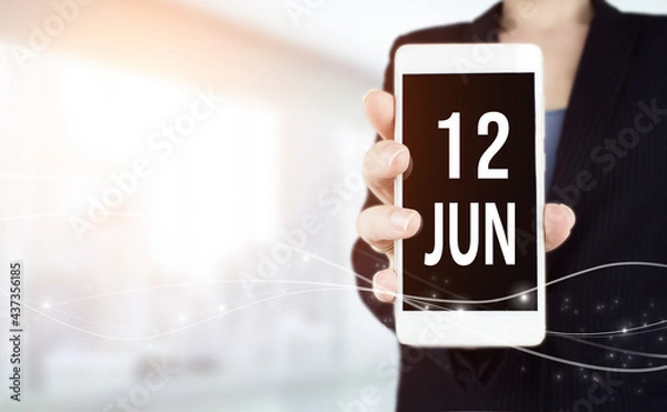 Fototapeta June 12nd. Day 12 of month, Calendar date. White smartphone with Calendar date in businesswoman hand on blurred background. Summer month, day of the year concept.