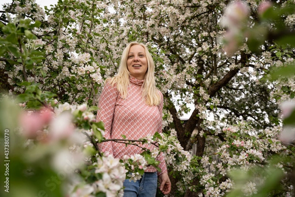 Obraz Blonde woman standing and posing in apple blossoms with dental braces, pink color