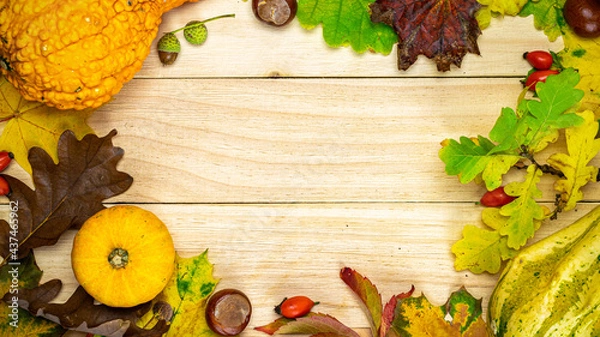 Fototapeta Flat lay autumn. Natural harvest with orange pumpkin, fall dried leaves, red berries and acorns, chestnuts on wooden background in shape frame. For seasonal offers and holiday post card, top view.
