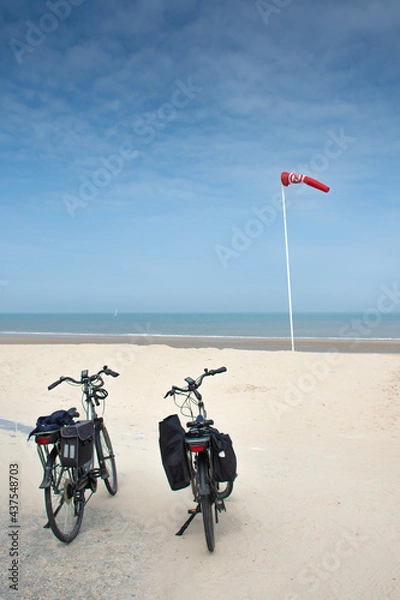 Fototapeta two bicycles on sandy beach and red  wind vane to forbid swimming in De Haan, Belgium