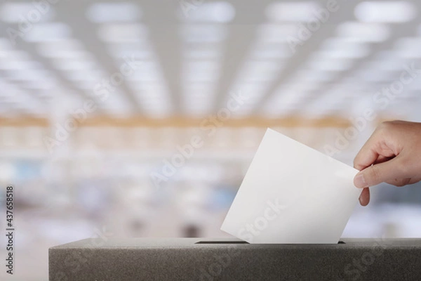 Fototapeta The voter holding ​ballot paper in the ballot box at polling station.