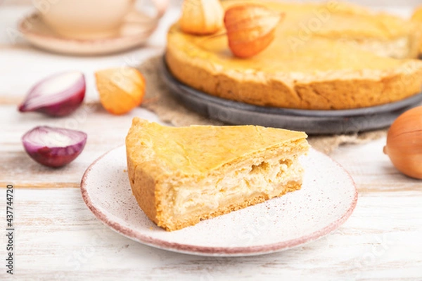Fototapeta Autumn onion pie and cup of coffee on white wooden background. Side view, selective focus.