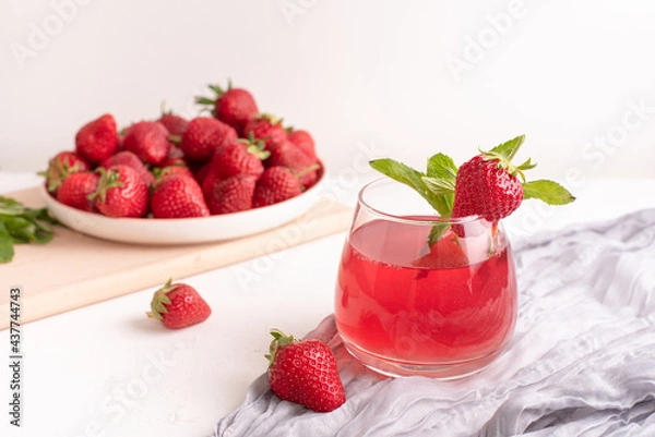 Fototapeta Glass with strawberry lemonade and strawberries on a table with textiles on a white background, summer drinks concept.