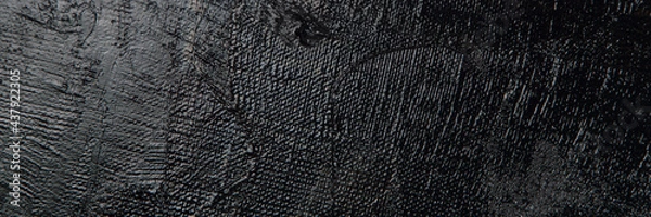Fototapeta Dark creative background - rough linen canvas unevenly covered with black primer, reflections of light. Toning, blurring, selective focus.