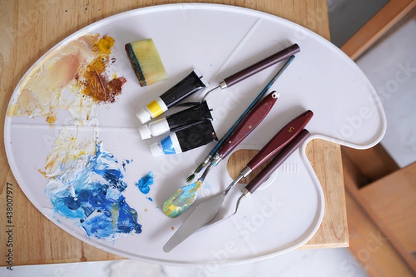 Fototapeta Acrylic sea and beach painting on drawing stand with palette and brush. Blue wave on golden sand hand painting with brush and knife palette technique. Art on canvas.