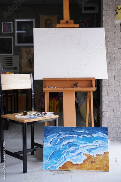 Fototapeta Acrylic sea and beach painting on drawing stand with palette and brush. Blue wave on golden sand hand painting with brush and knife palette technique. Art on canvas.