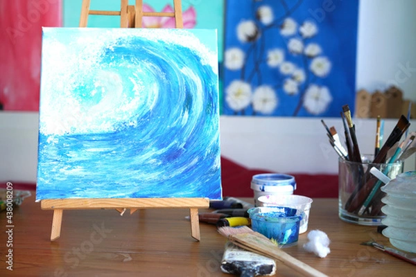 Fototapeta Painter paint acrylic on canvas with brush with blue on frame. Artwork as hobby or occupation for artist. Woman creates artwork by mix color and decors picture as hard copy art.