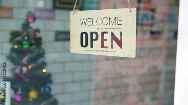 Fototapeta Open and closed flip sign in front of coffee shop and restaurant glass door. Wooden sign with wording of place's status. Say sorry we're closed. Please come back again and another side.