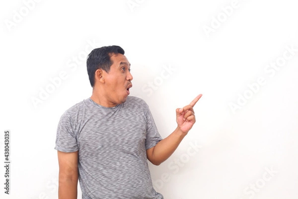 Fototapeta Wow and shocked face of Asian man point to present an empty space of content. Advertising model concept.