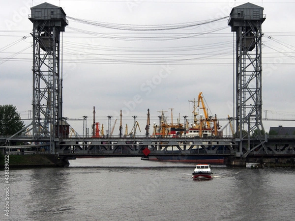 Fototapeta Drawbridge on the background of gantry cranes and ships in the sea, cargo port. Terminal of a sea or cargo port.