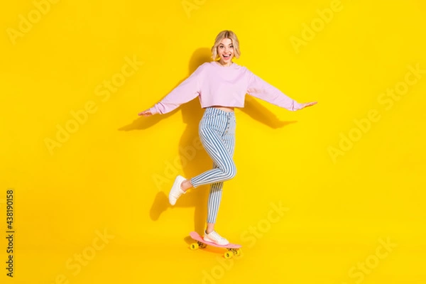 Fototapeta Full length photo of young excited girl happy positive smile ride skateboard speed isolated over yellow color background