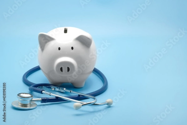 Fototapeta Piggy bank with stethoscope isolated on light blue background with copy space. Health care financial checkup or saving for medical insurance costs concept.